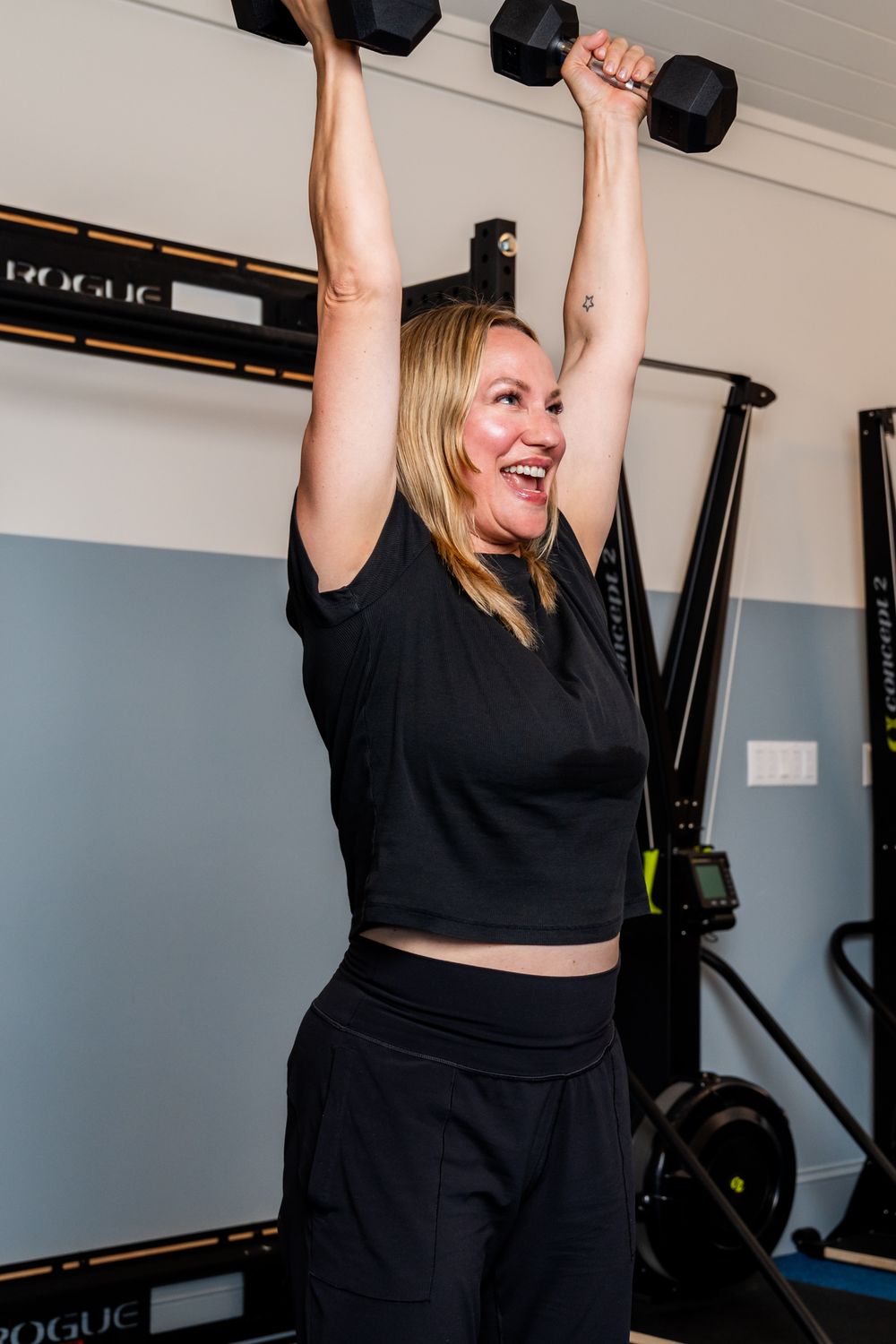 Person in black athletic wear lifting weights during a workout session.