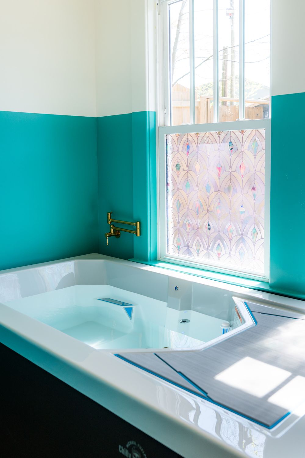 Modern therapy room features sunlit white bathtub against turquoise walls.