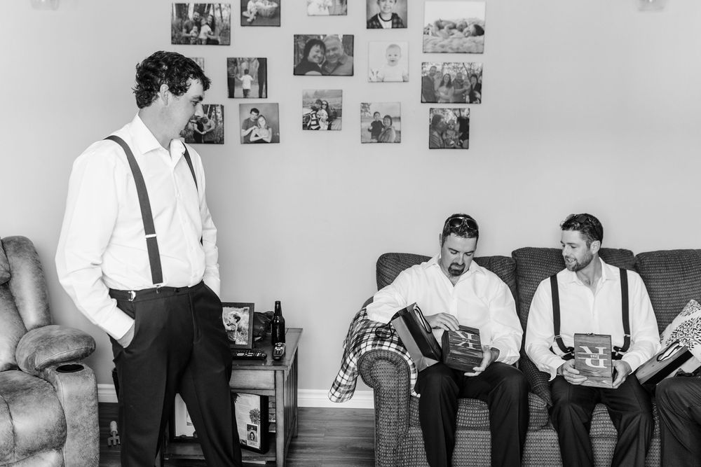 Group of men in formal attire standing together and talking in a room decorated with photographs on the wall.