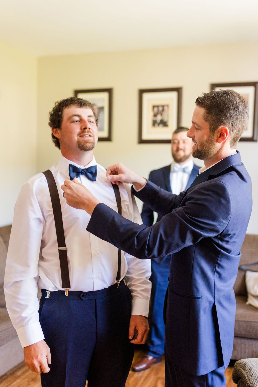 Wedding party preparations show groomsmen helping with formal attire and bow ties.