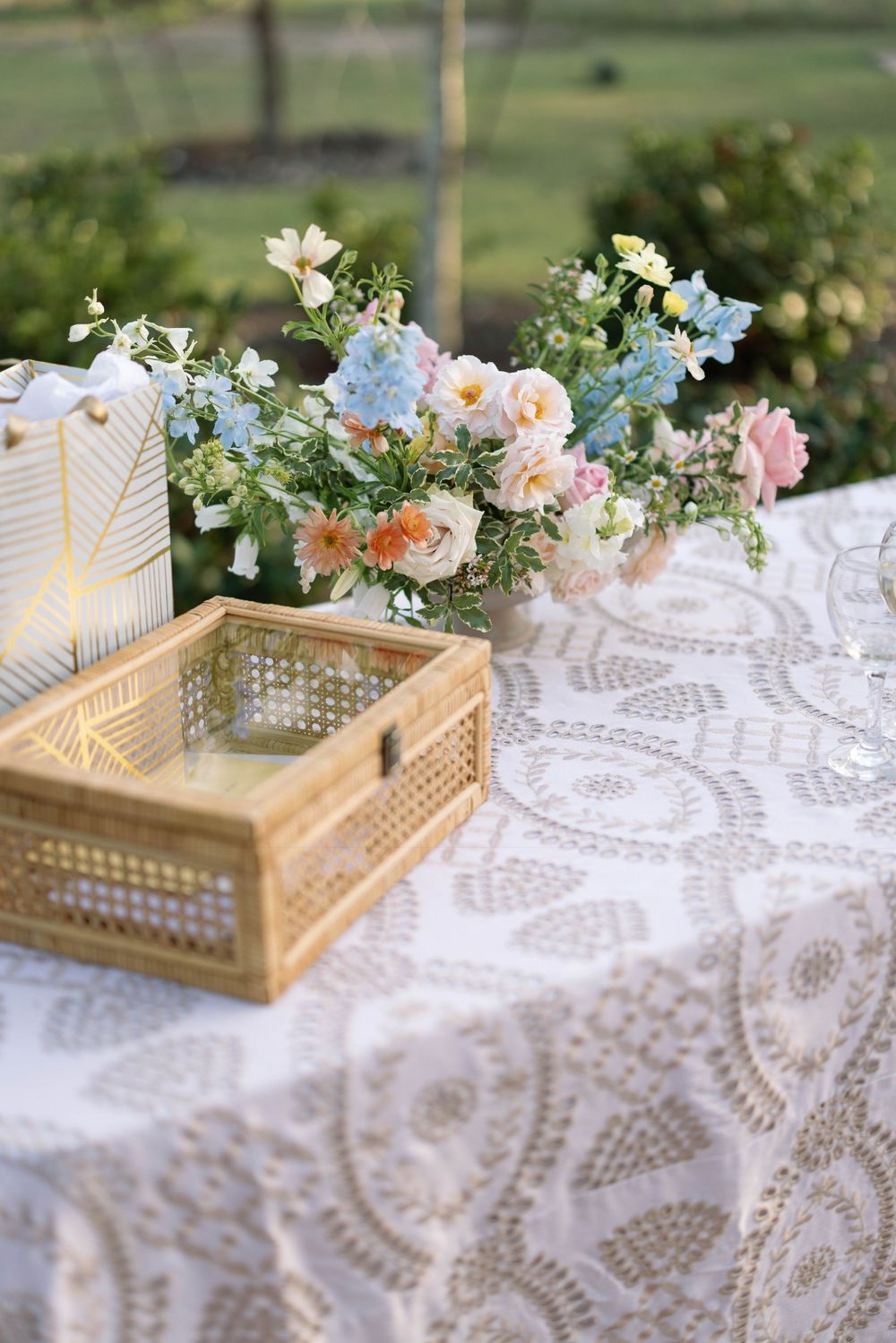 Elegant wooden lattice tray with lace tablecloths and delicate floral arrangements in soft pastel colors set for outdoor dining.