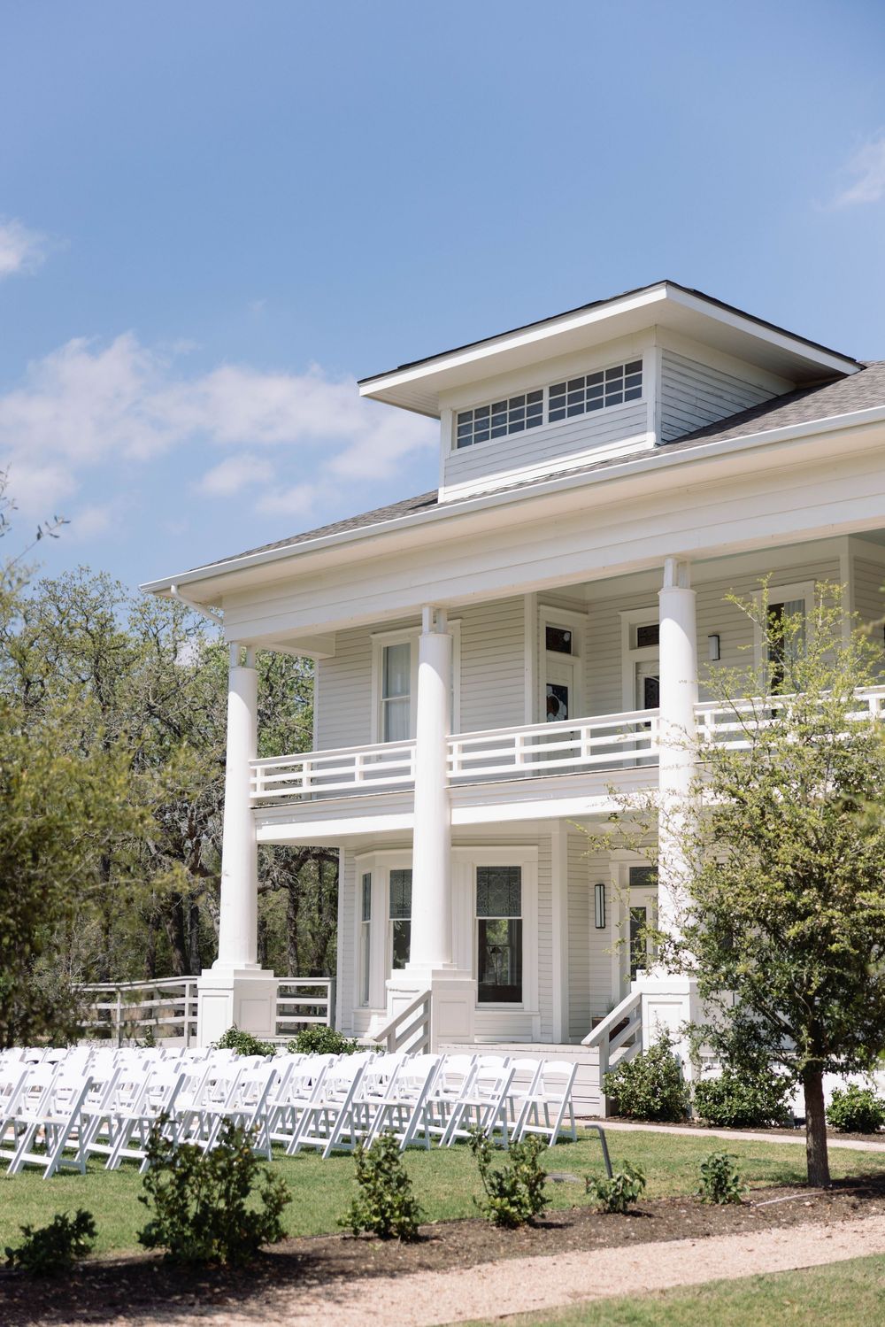 A white coastal-style house with wrap-around porch and classic columns is shown from multiple angles under blue sky.