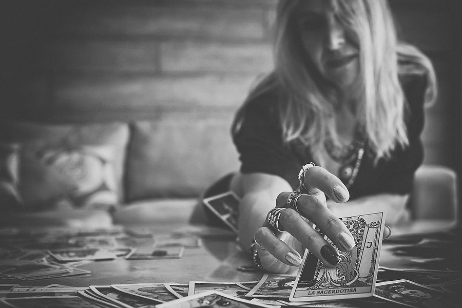 Hands writing in a journal on a rustic wooden table in moody black and white photography.