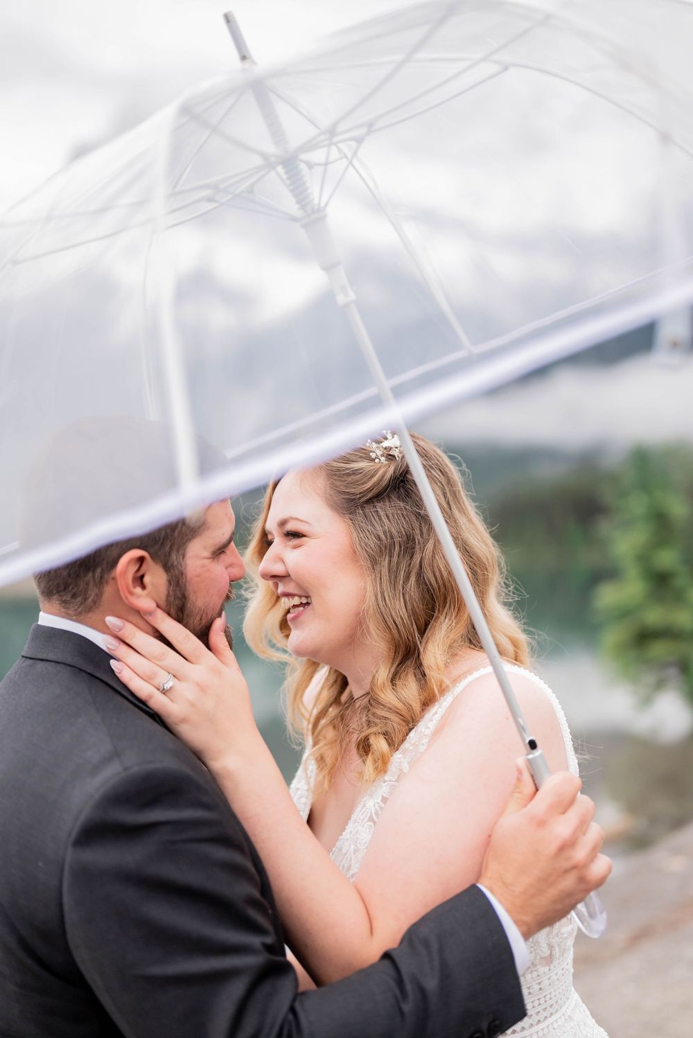 Newlywed couple shares an intimate moment under a clear canopy during their wedding celebration.