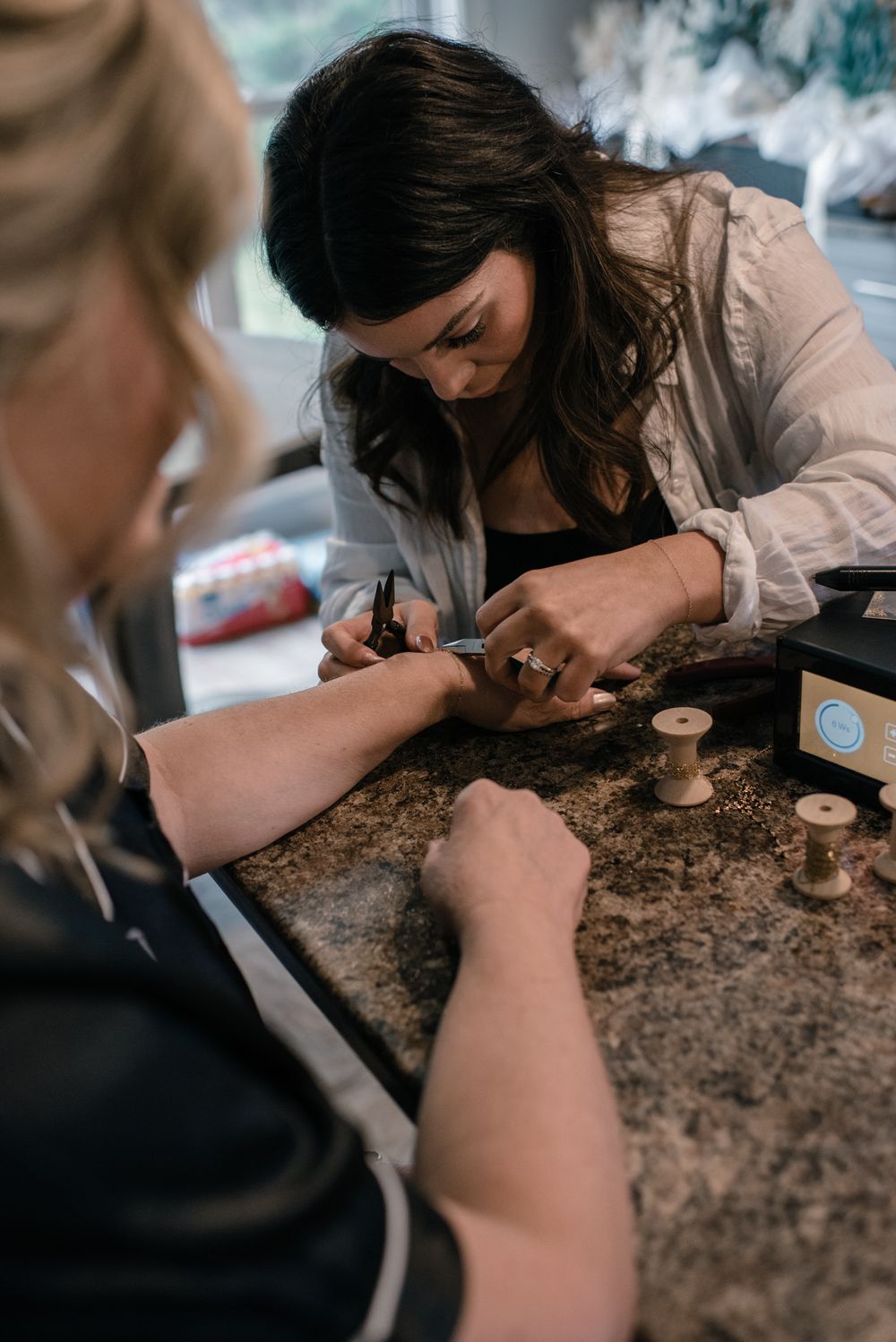 A person gives a manicure on a textured stone counter with scattered nail supplies and tools for beauty treatment.