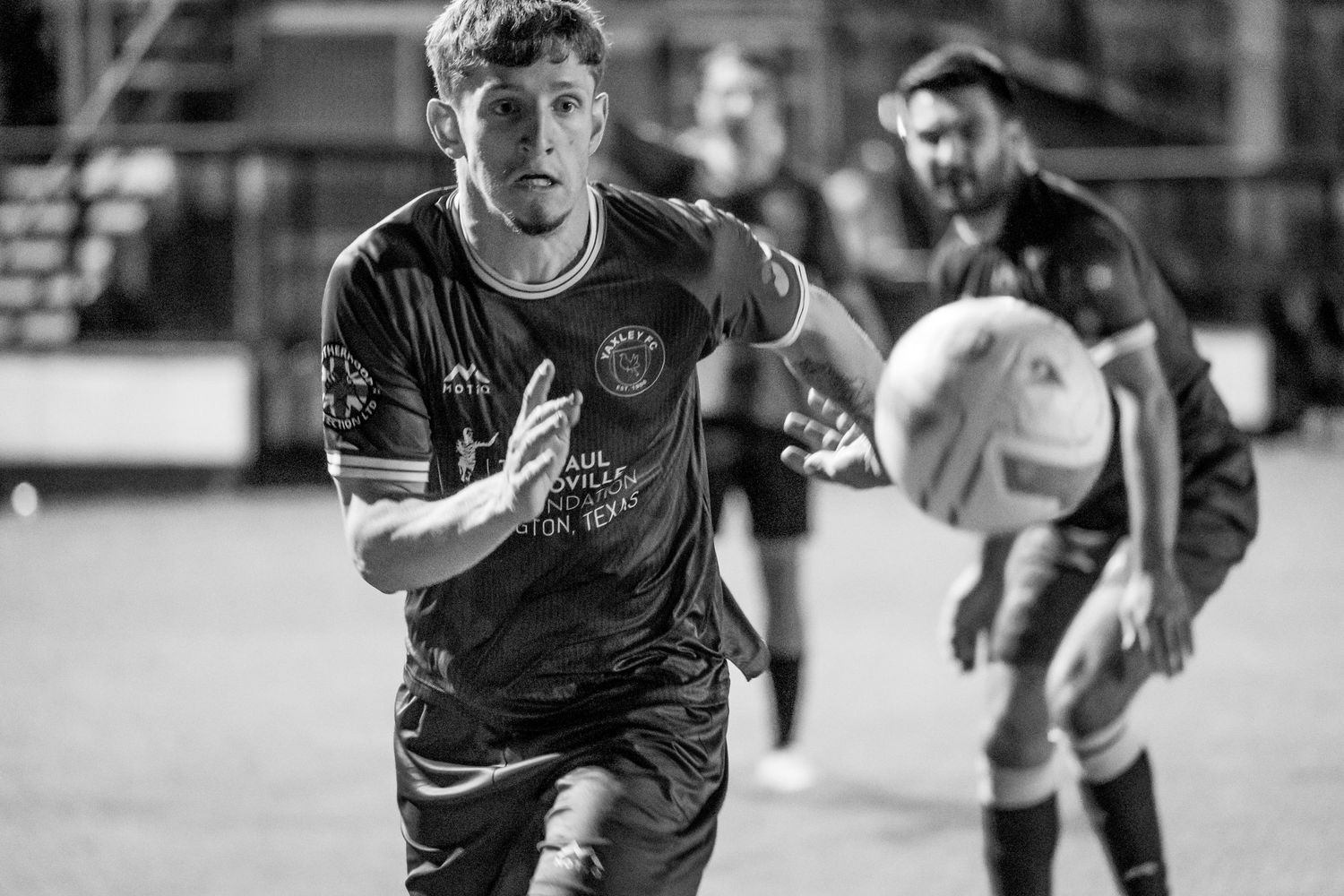 Black and white action shot of a soccer player running during a match.