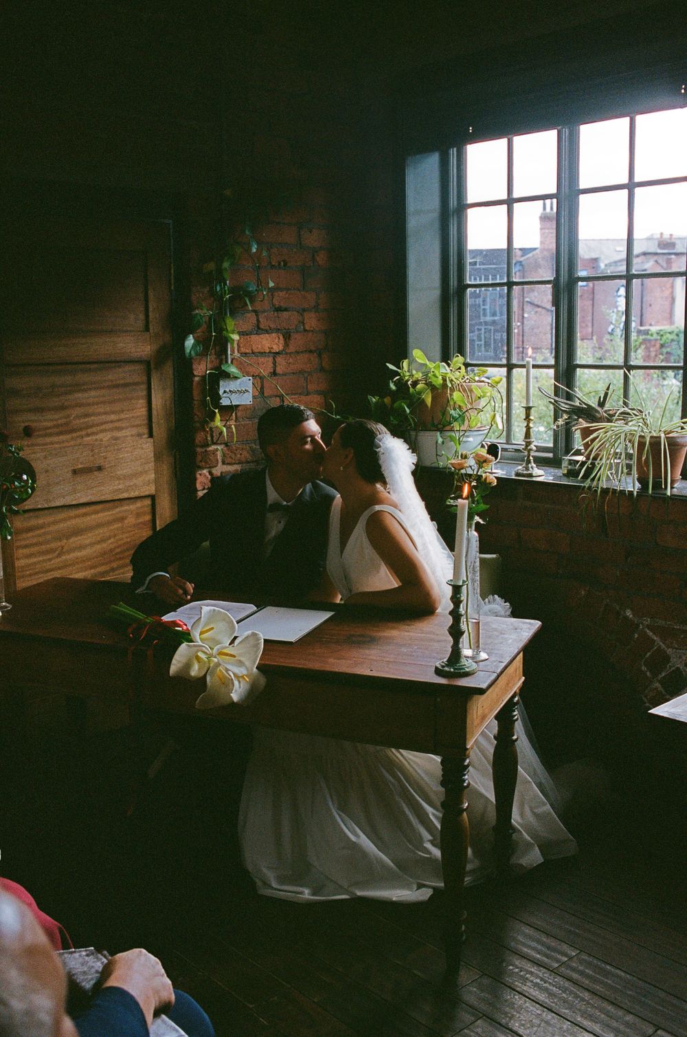 A vintage-style scene with a desk by a window in a brick-walled room with natural light and candle holder.
