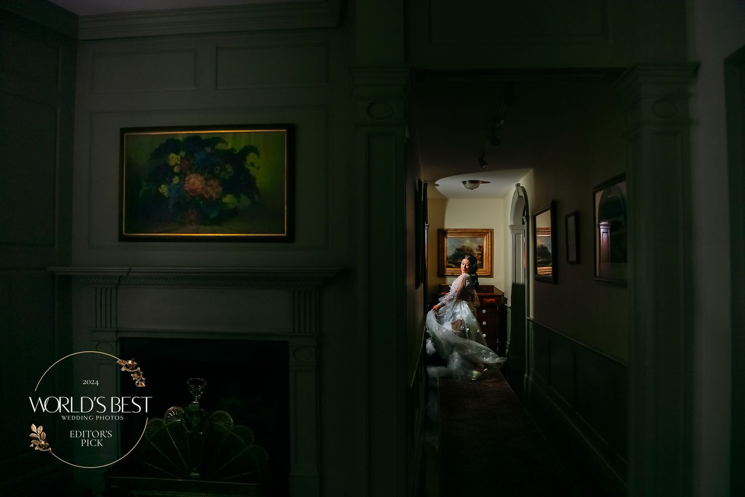 Dark moody interior photograph showing a doorway with dramatic lighting and a framed artwork on the wall.