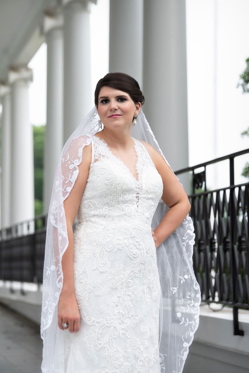 Bridal portraits showcasing intricate lace details and flowing veil against white columns and iron railings.