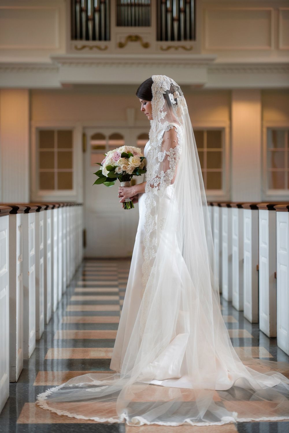 Dramatic church bridal portraits showing flowing cathedral veil and train against white pews and pipe organ.