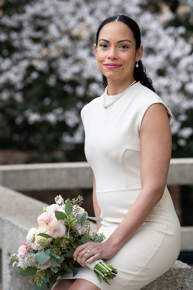 A spring bridal portrait with white cherry blossoms and a romantic bouquet featuring soft pink and white flowers.
