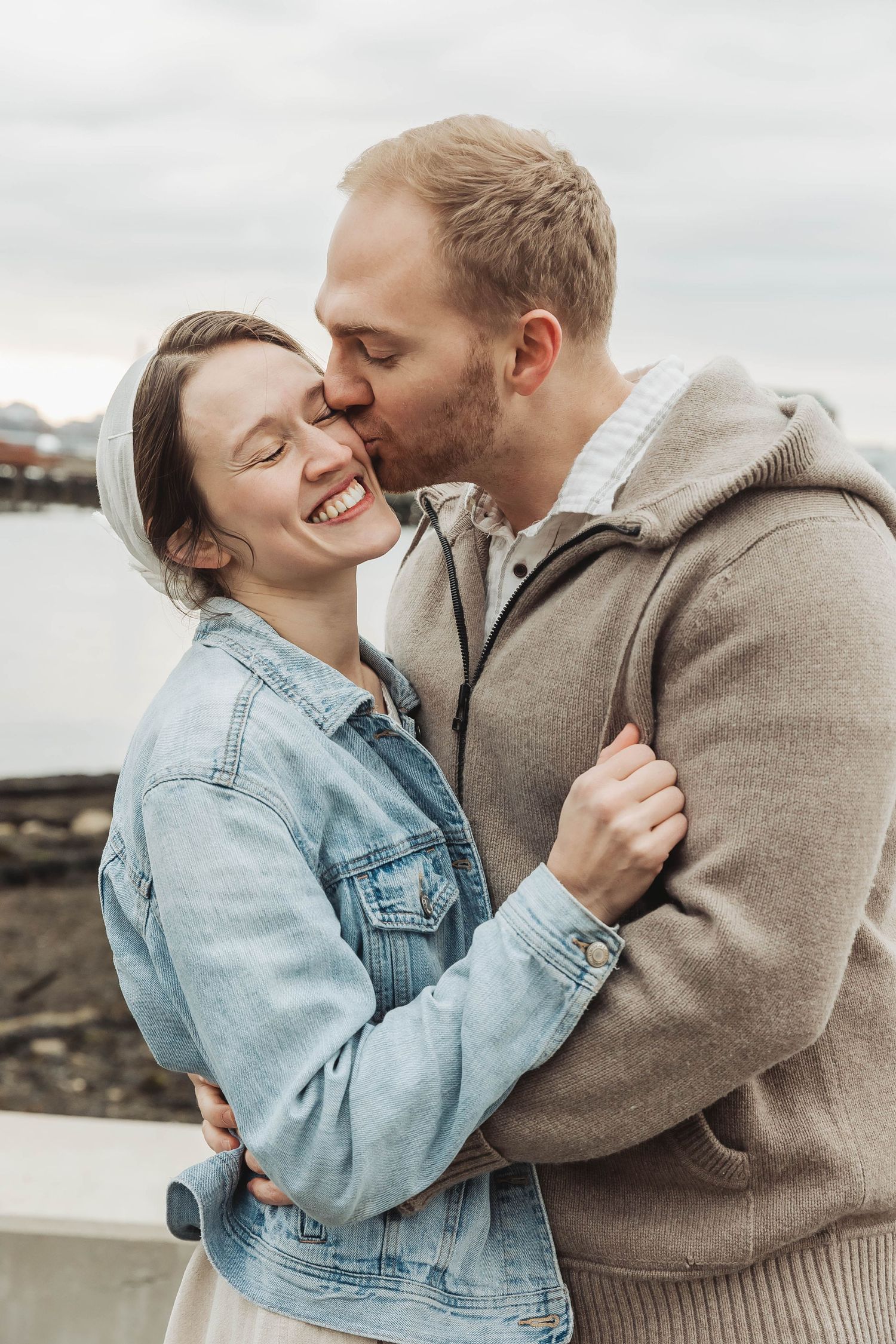 A couple shares an intimate moment while embracing near the waterfront.
