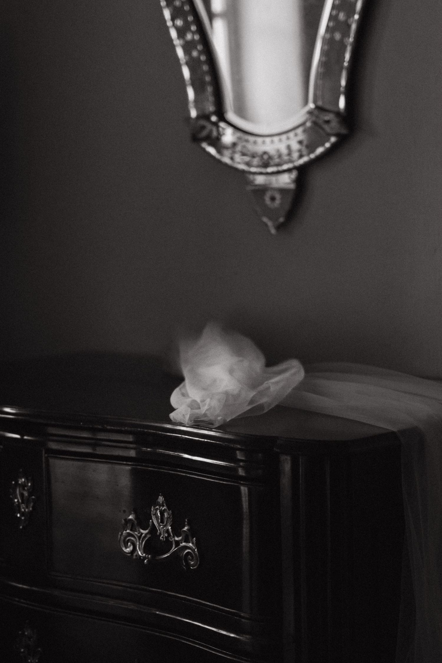 A vintage-style black and white detail shot of decorative furniture and delicate fabric in soft focus.