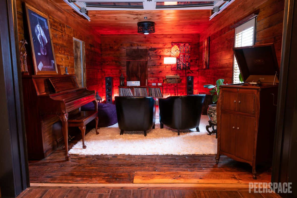 Intimate home theater room with red ambient lighting, wooden walls, and comfortable seating arrangement.