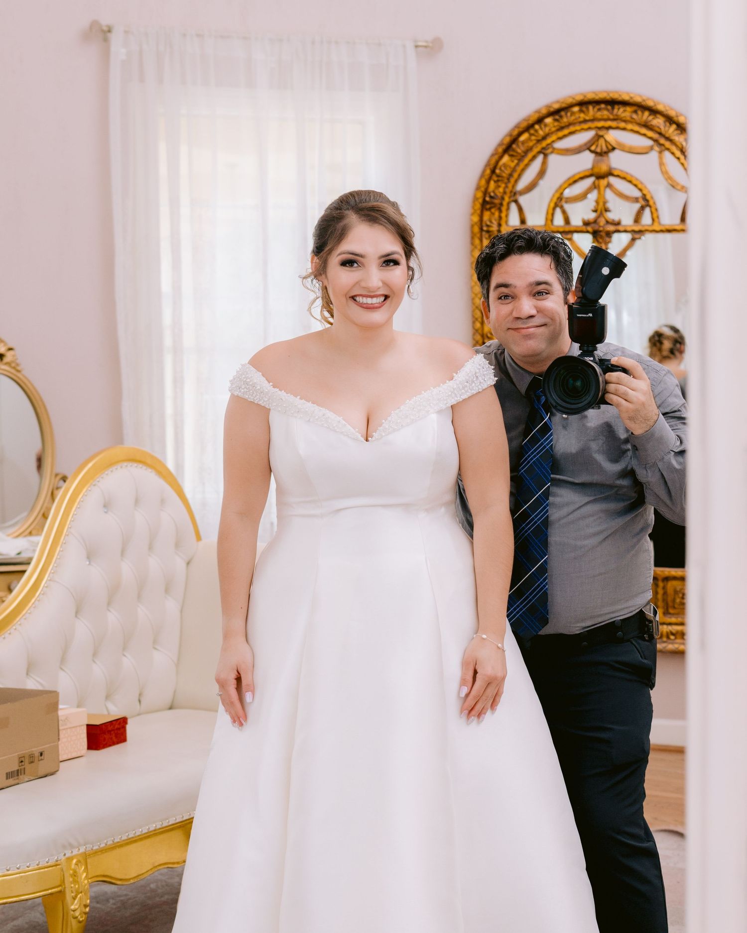 A wedding dress fitting scene in an elegant room with ornate gold mirrors and white curtains.