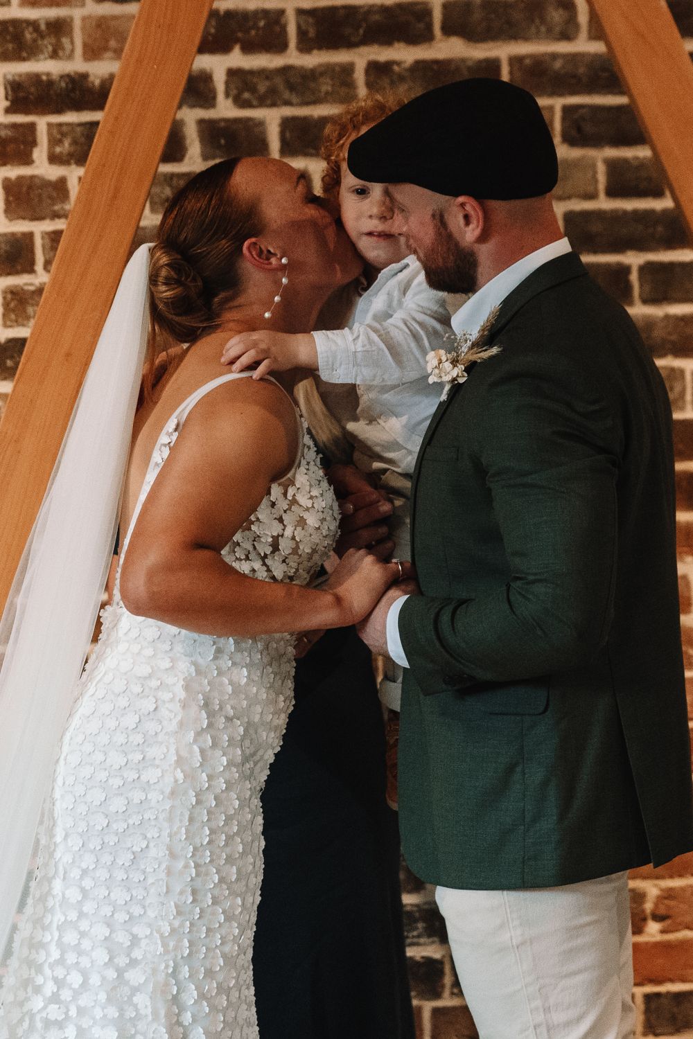 Intimate wedding moment shared under a wooden triangle arch during ceremony.