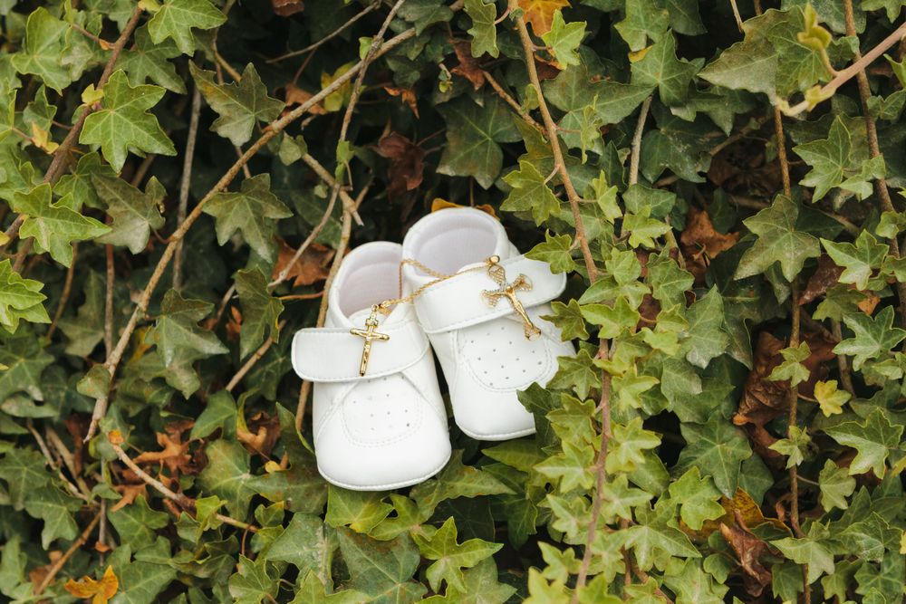Detail of baby's shoes with cross medal by NYC family photographer Paula Ortiz.