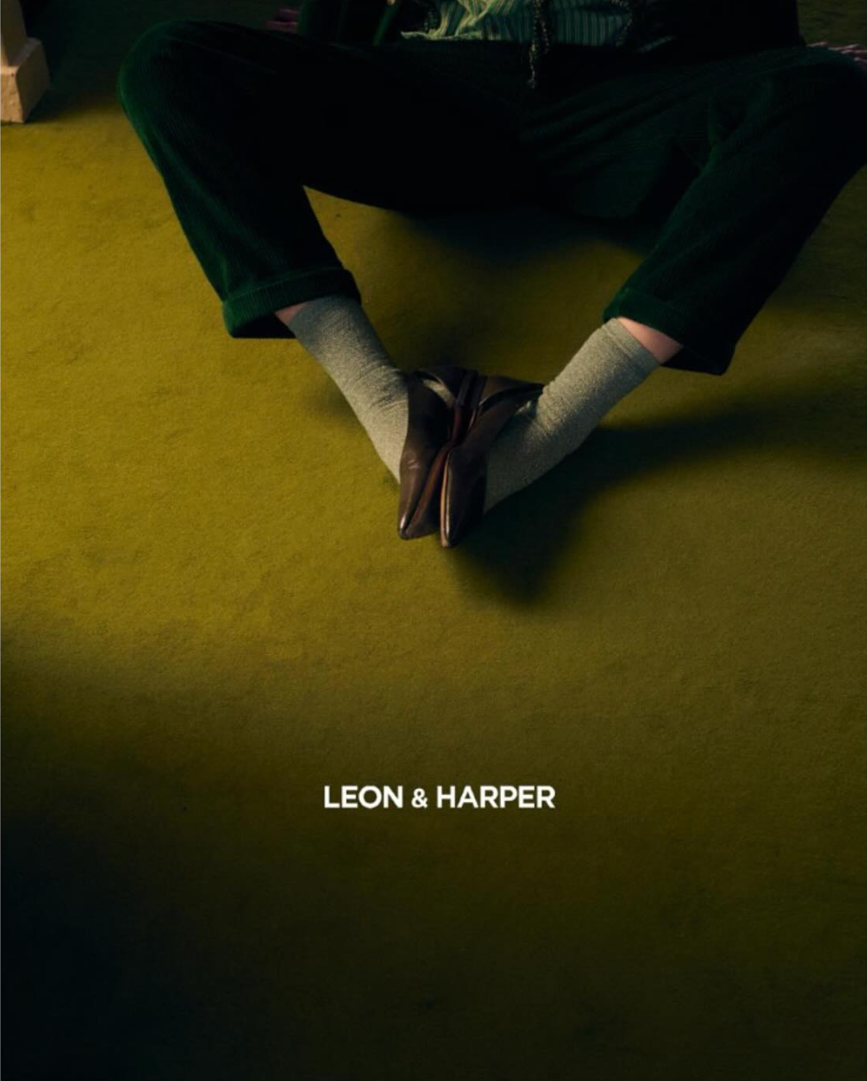 Leon & Harper fashion brand advertisement showing crossed feet on a dark green background.