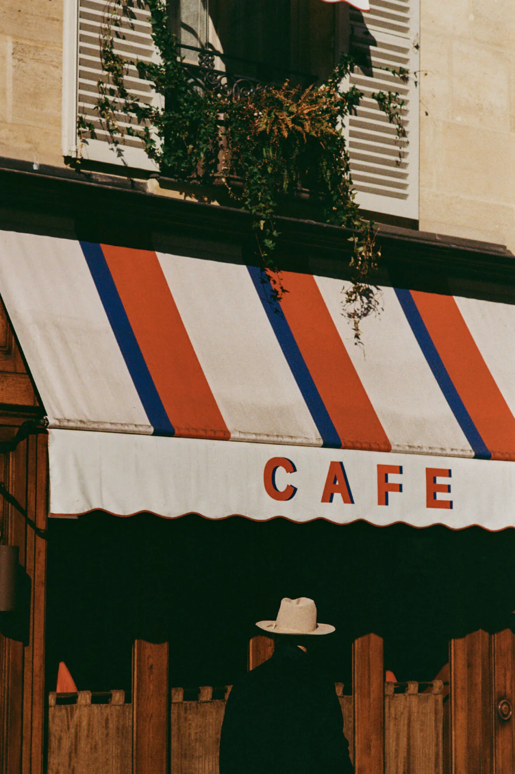 A striped cafe awning with red and blue stripes above a silhouetted entrance.