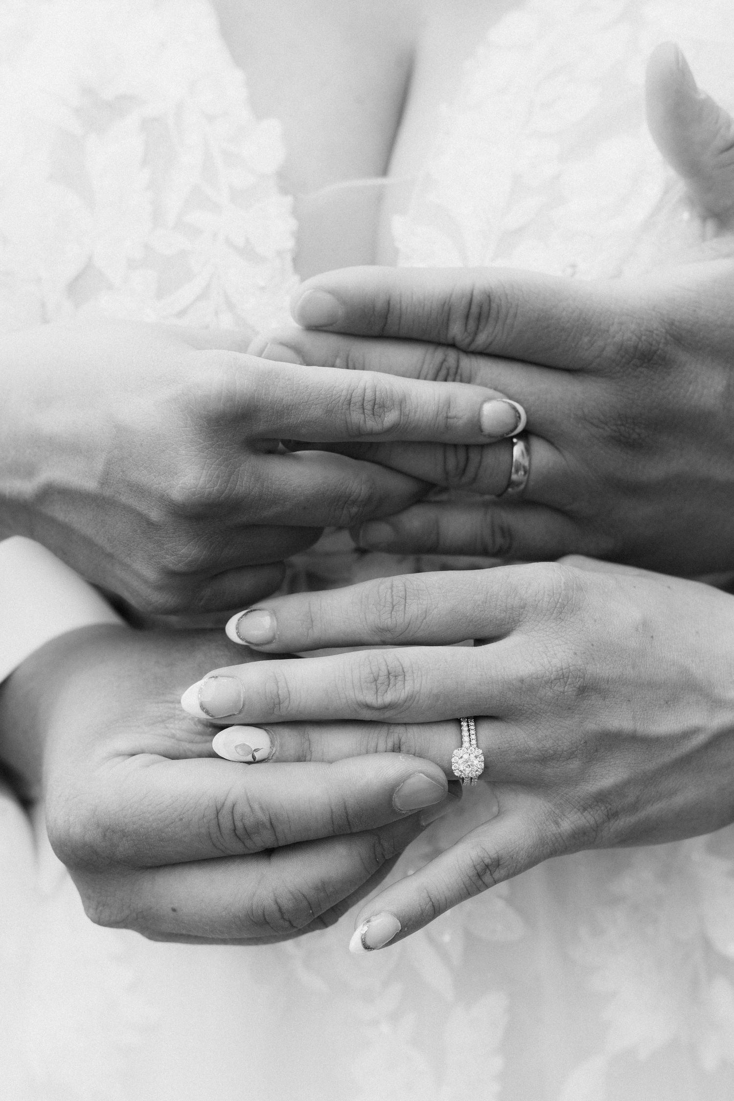 Close-up black and white photo of hands with wedding rings showing special moment.