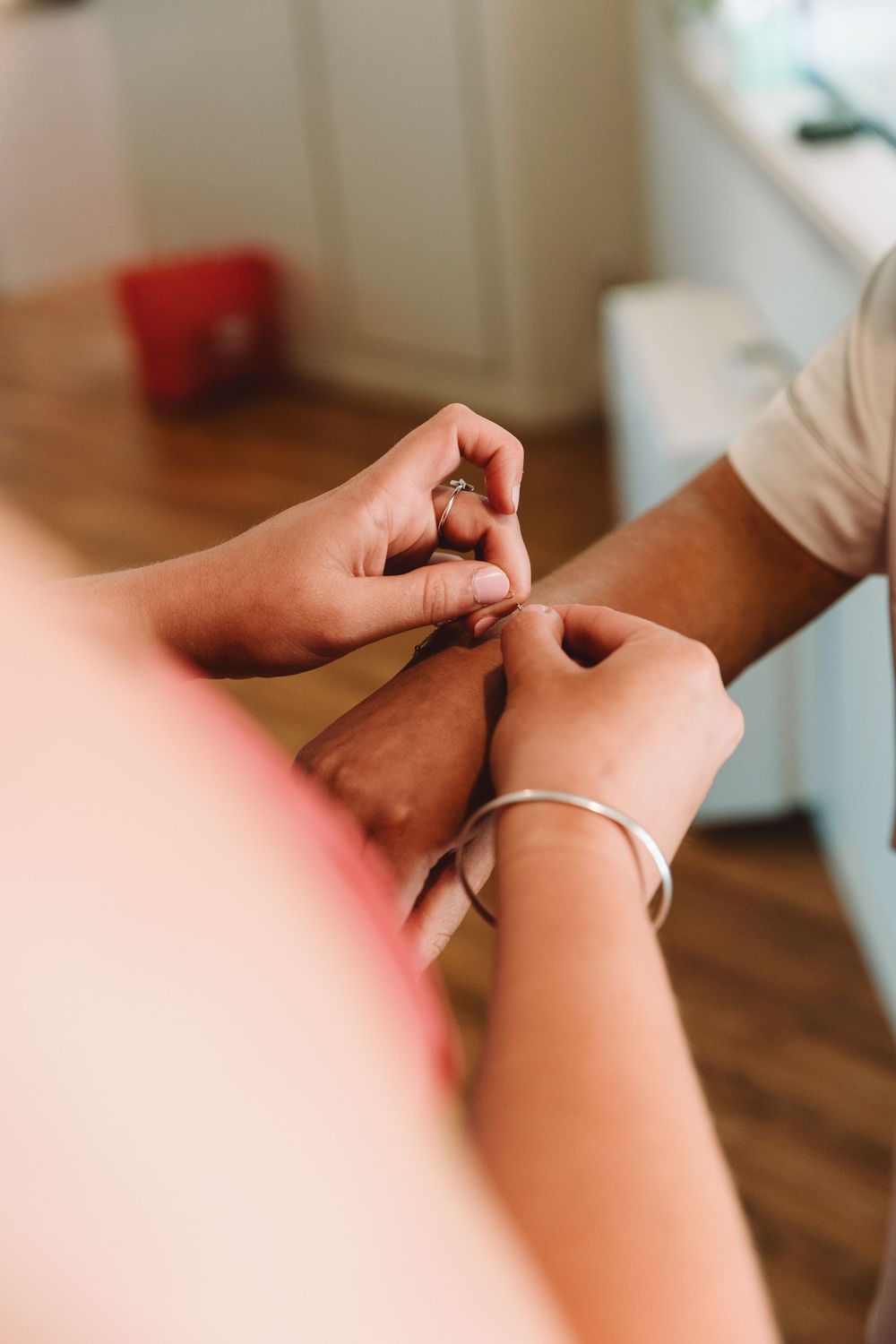Close-up of hands adjusting jewelry during wedding preparations.