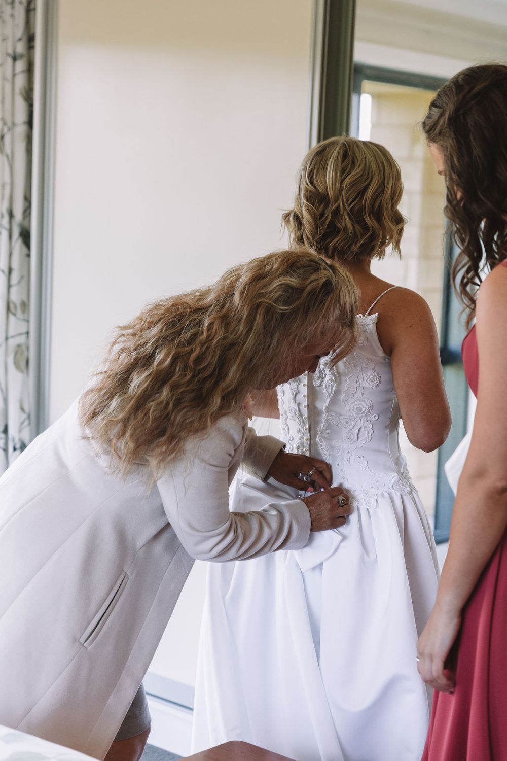 Wedding preparation scene showing dress adjustments and final touches.
