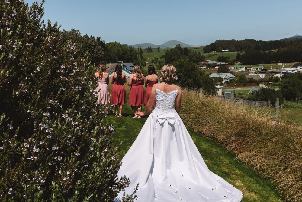 Wedding party walking along hillside path with scenic valley view.