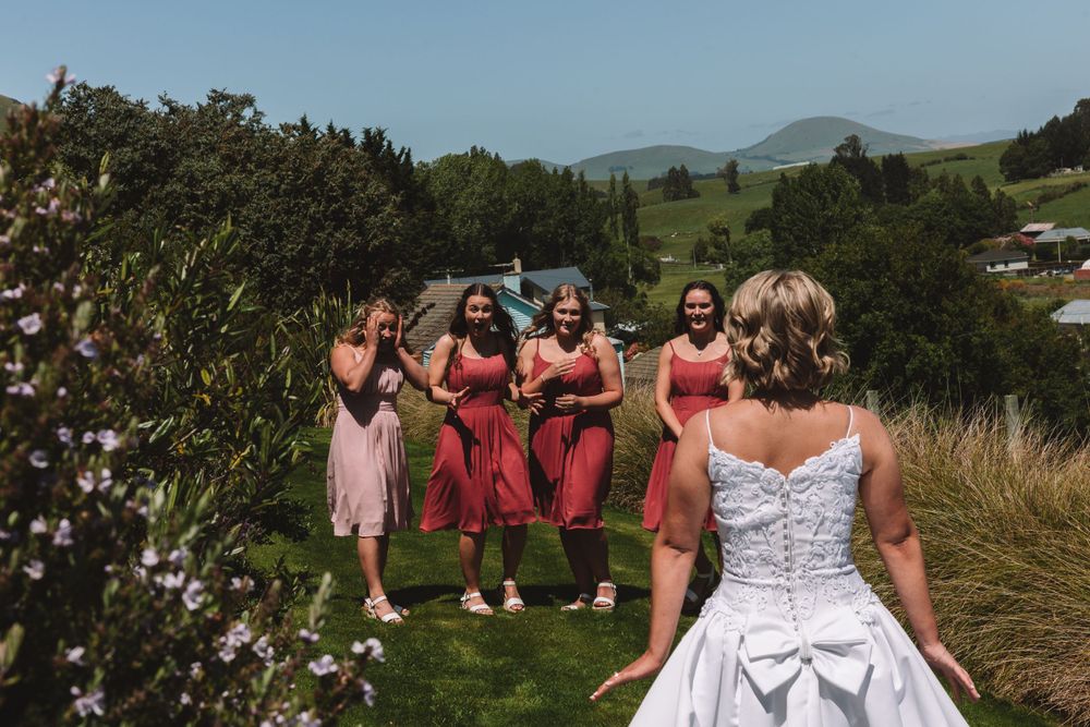A bridal party poses against a scenic hillside backdrop with mountains in the distance.
