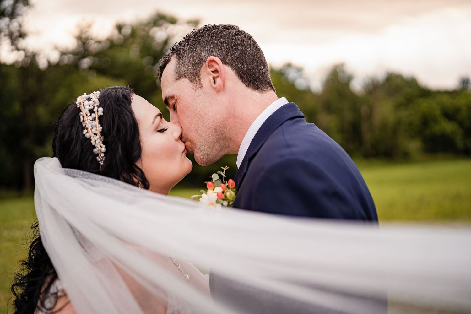 A romantic wedding portrait with a flowing veil caught in the golden light.