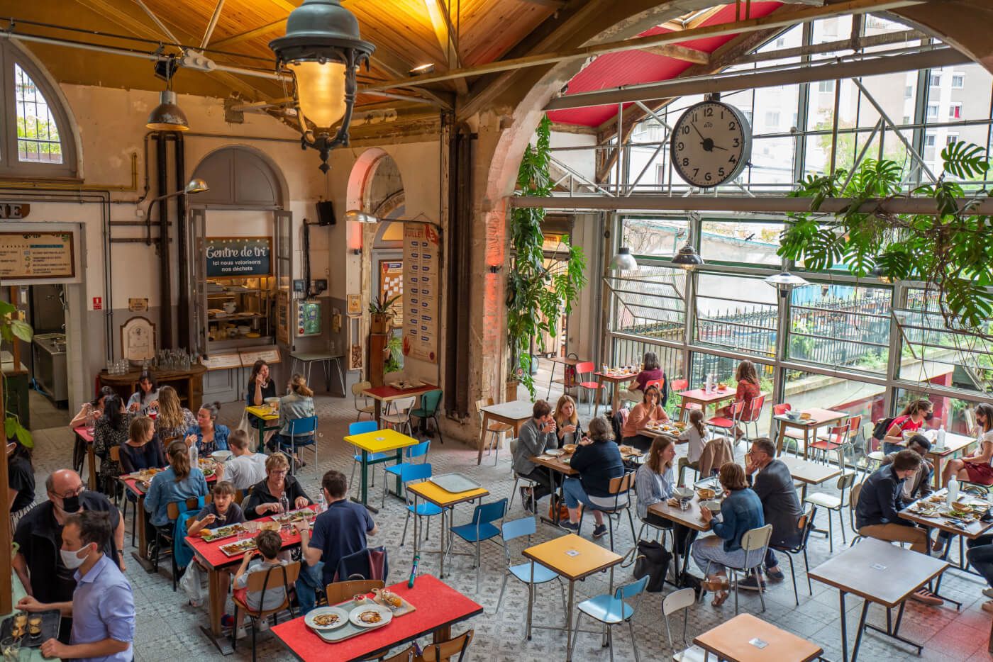 Bustling indoor-outdoor cafe with vintage decor and diners enjoying meals under wooden beams.