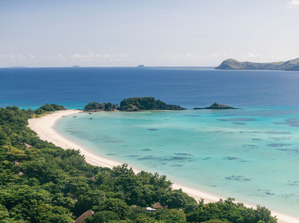A stunning beach at Amanpulo, Philippines, featuring a crystal-clear blue ocean.