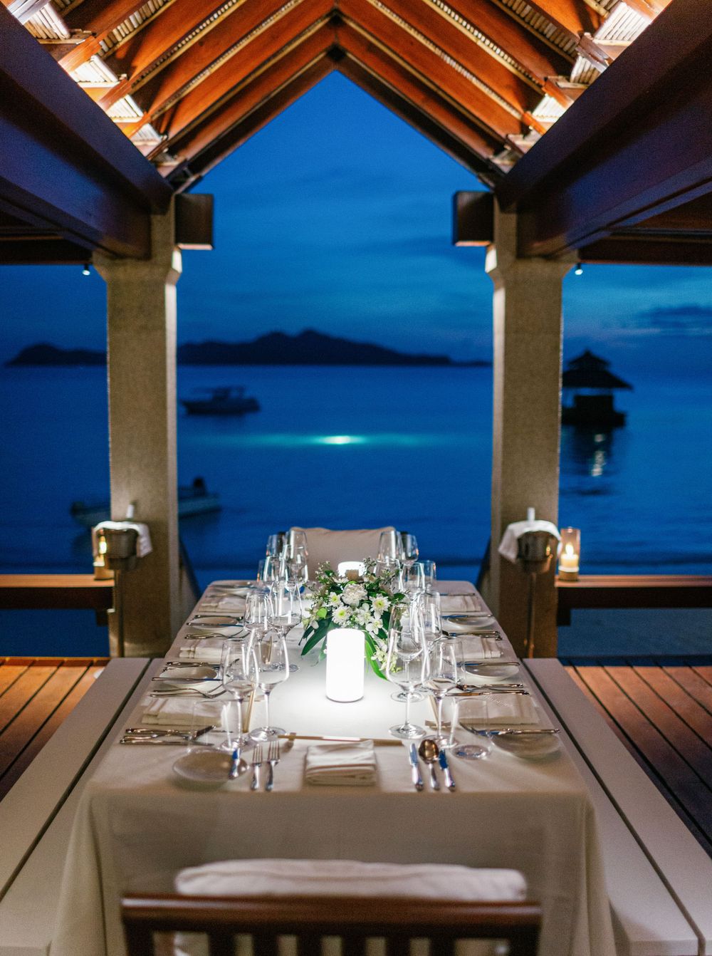 Wedding reception at Amanpulo, Philippines: Outdoor venue adorned with tables, flowers, and twinkling lights.
