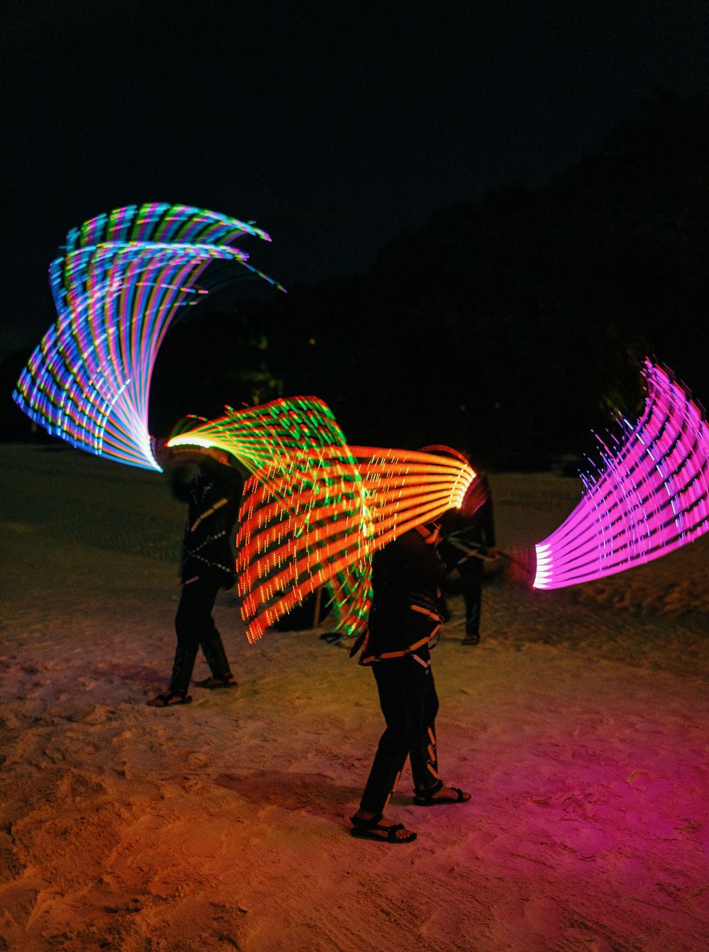 People playing with colorful lights at a wedding celebration in Amanpulo, Philippines.