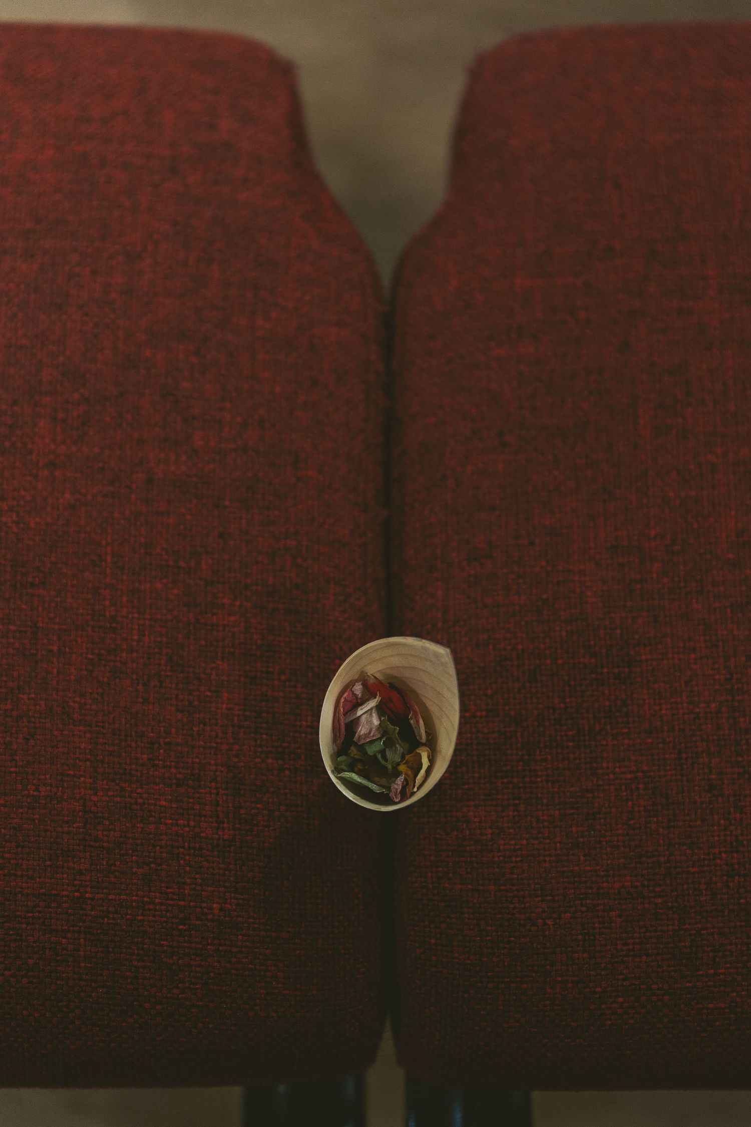 Small decorative flower arrangement placed between two red upholstered theater seats.