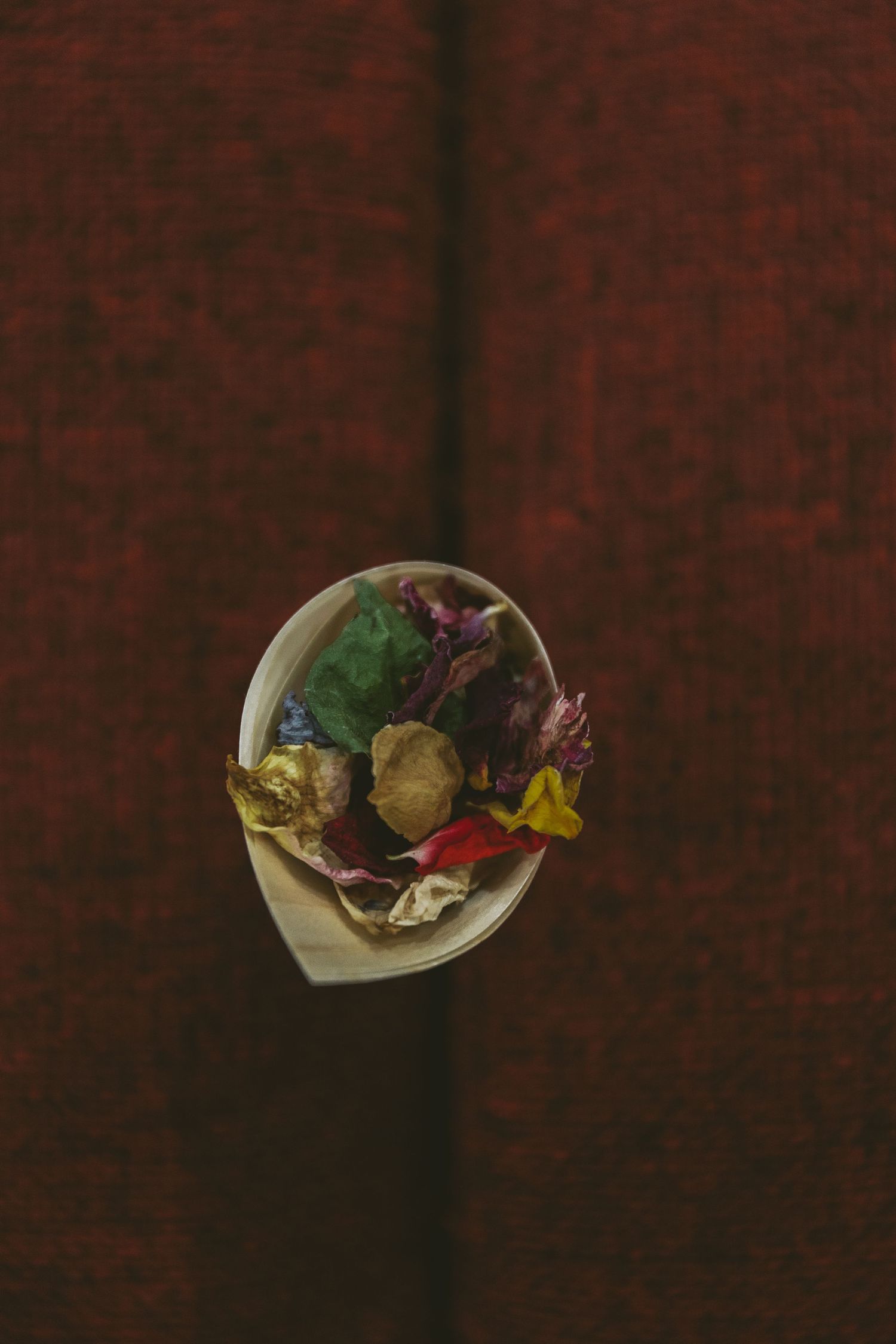 Overhead view of colorful floral petals and decorations in a white paper cone.