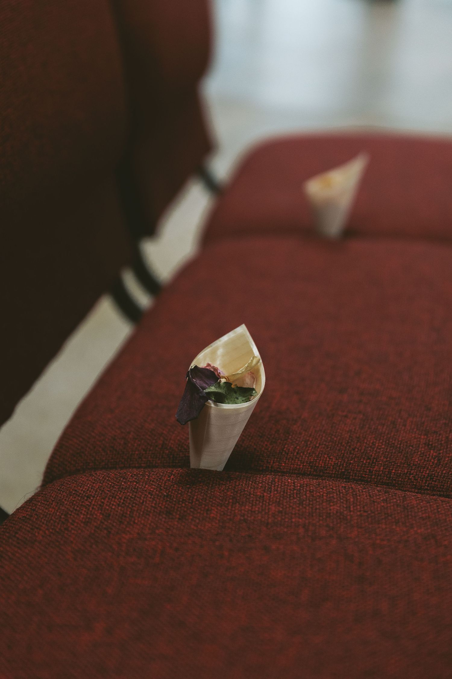 White paper cones with floral petals placed on red theater seats.