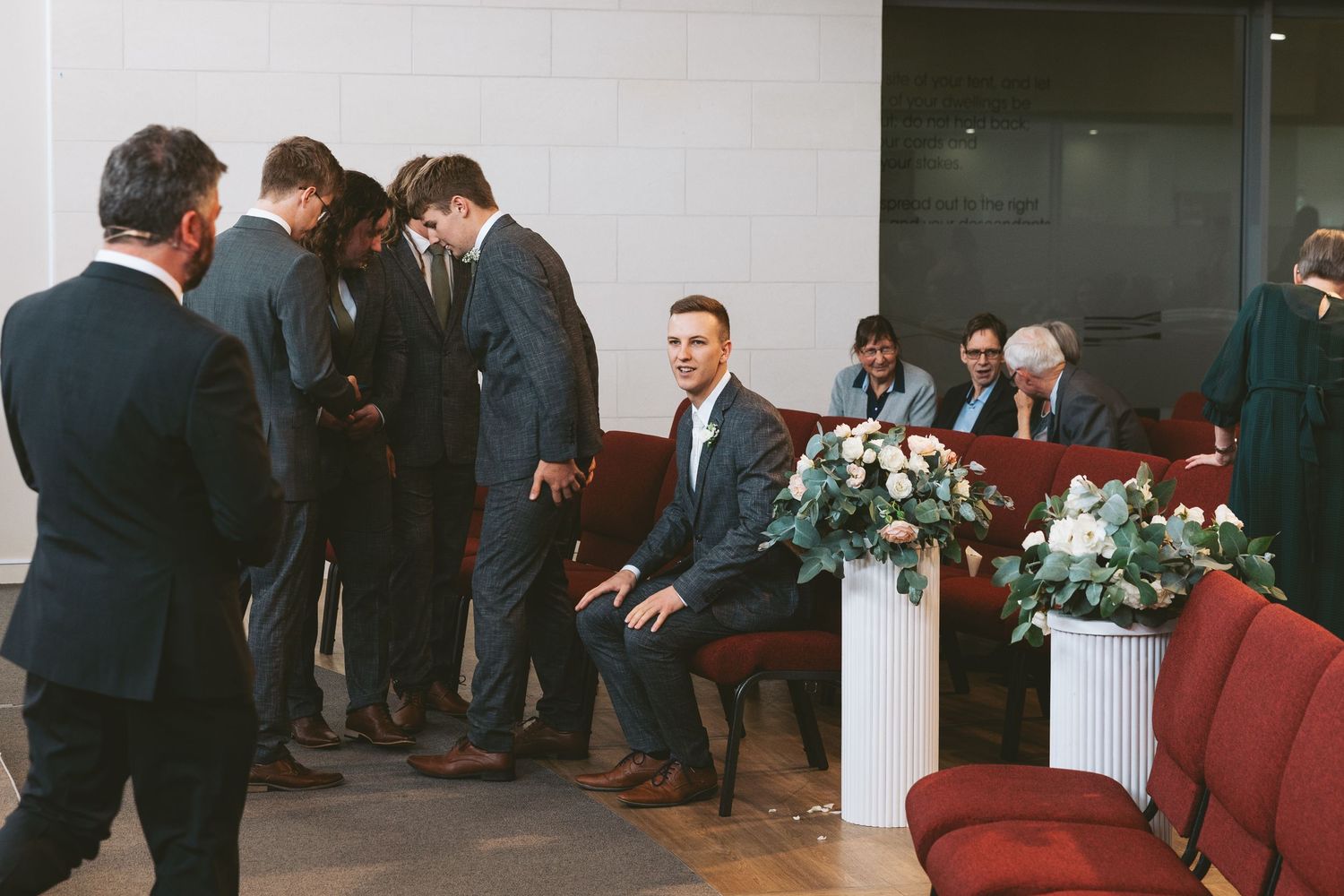 Interior of wedding venue with formal gathering and floral decorations.