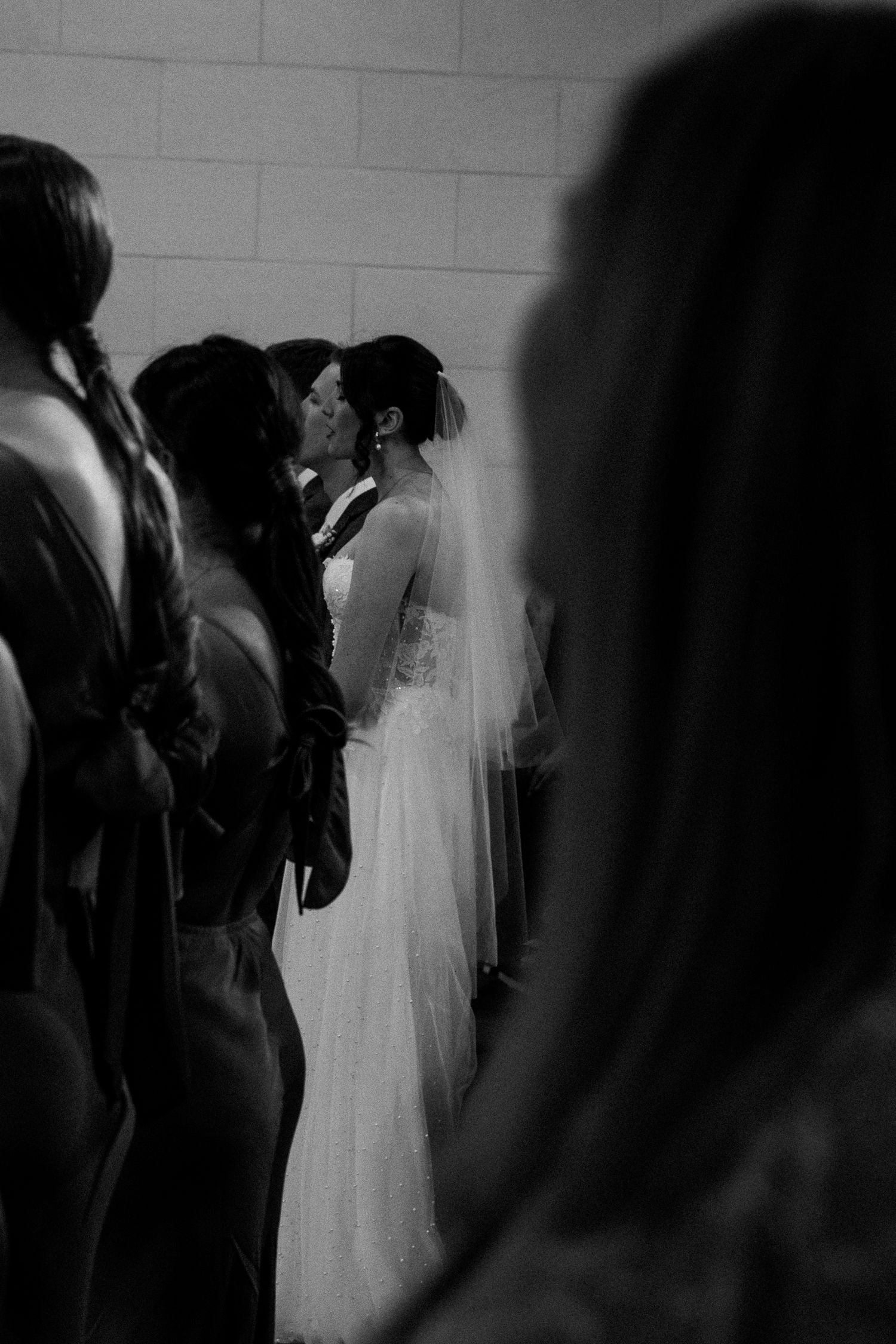 Dramatic black and white shot of wedding ceremony attendees in silhouette.