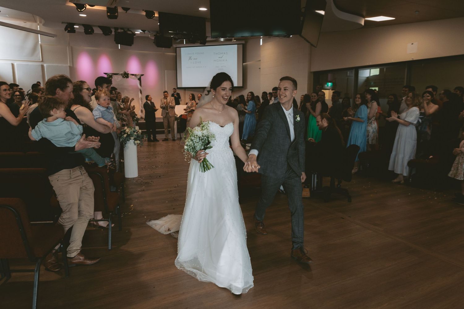 Newlyweds make their grand entrance at reception while guests cheer.