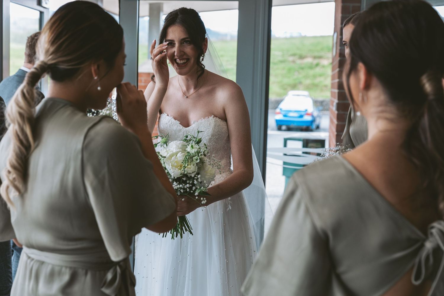 A white wedding dress and delicate bouquet of baby's breath flowers are shown during preparation moments.