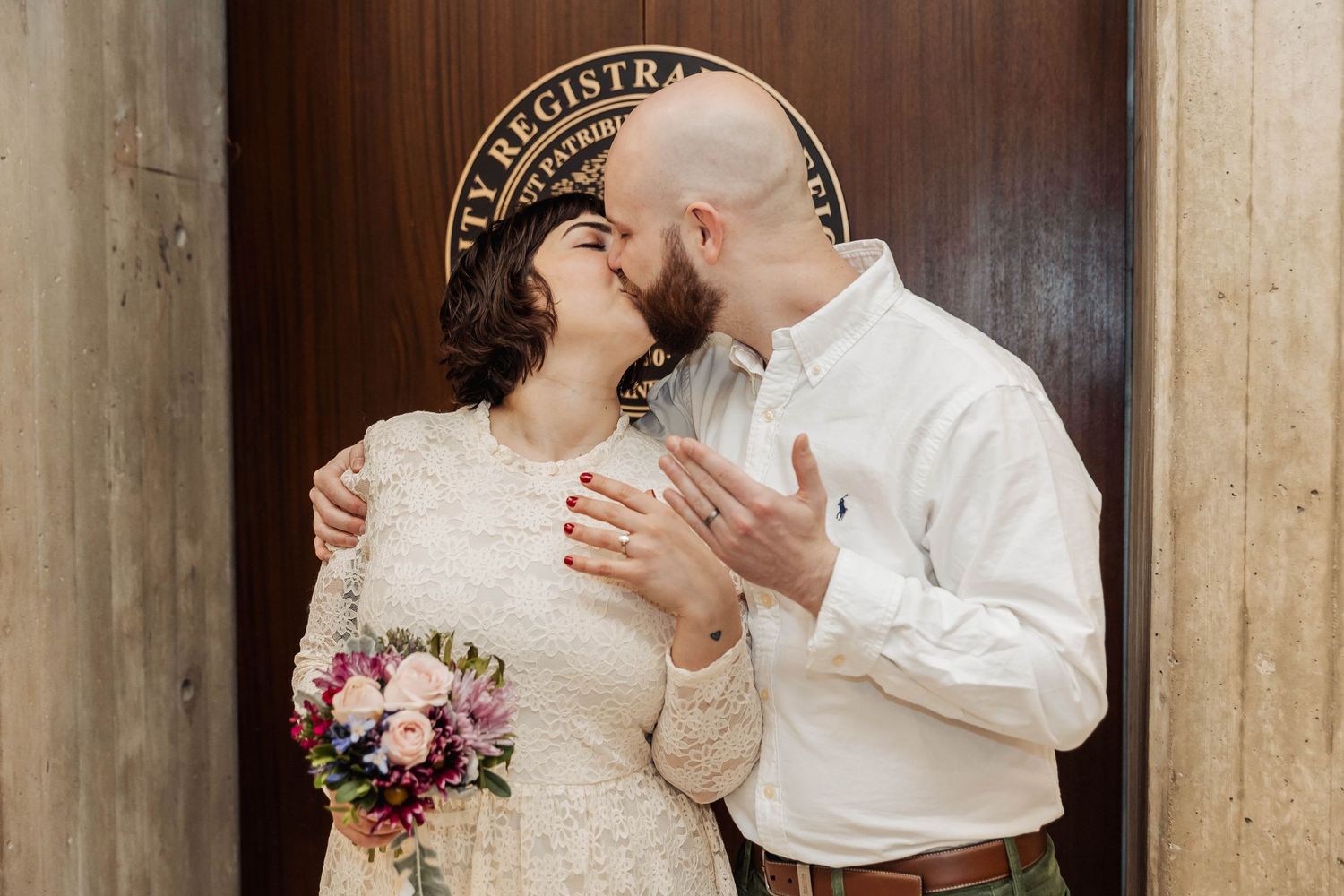 A romantic moment captured at a civil ceremony with vintage decor and pink floral bouquet.