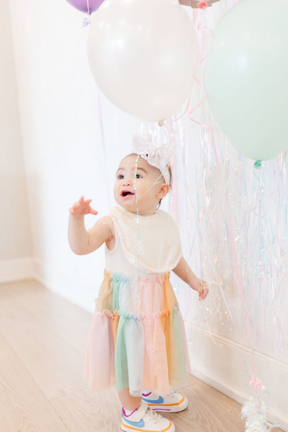 Baby girl wearing colourful outfit for her first birthday in Toronto party room, by event photographer Jess GC Photography