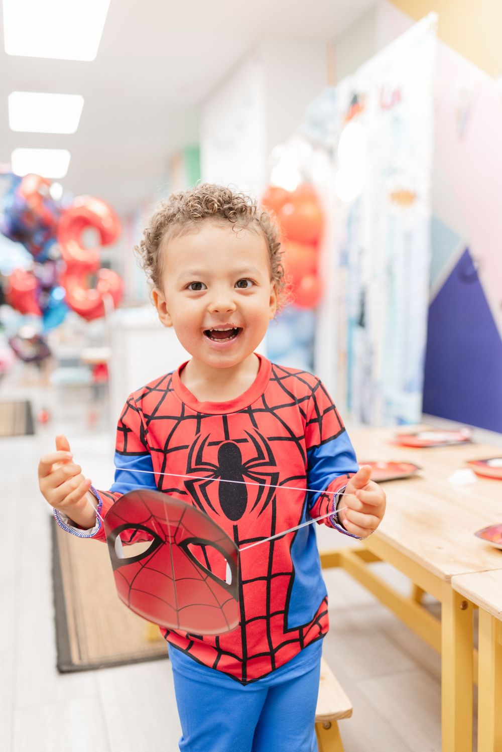 Little boy holding spider man mask and smiling at his third birthday party in Toronto kids birthday venue, captured by Jess GC Photography