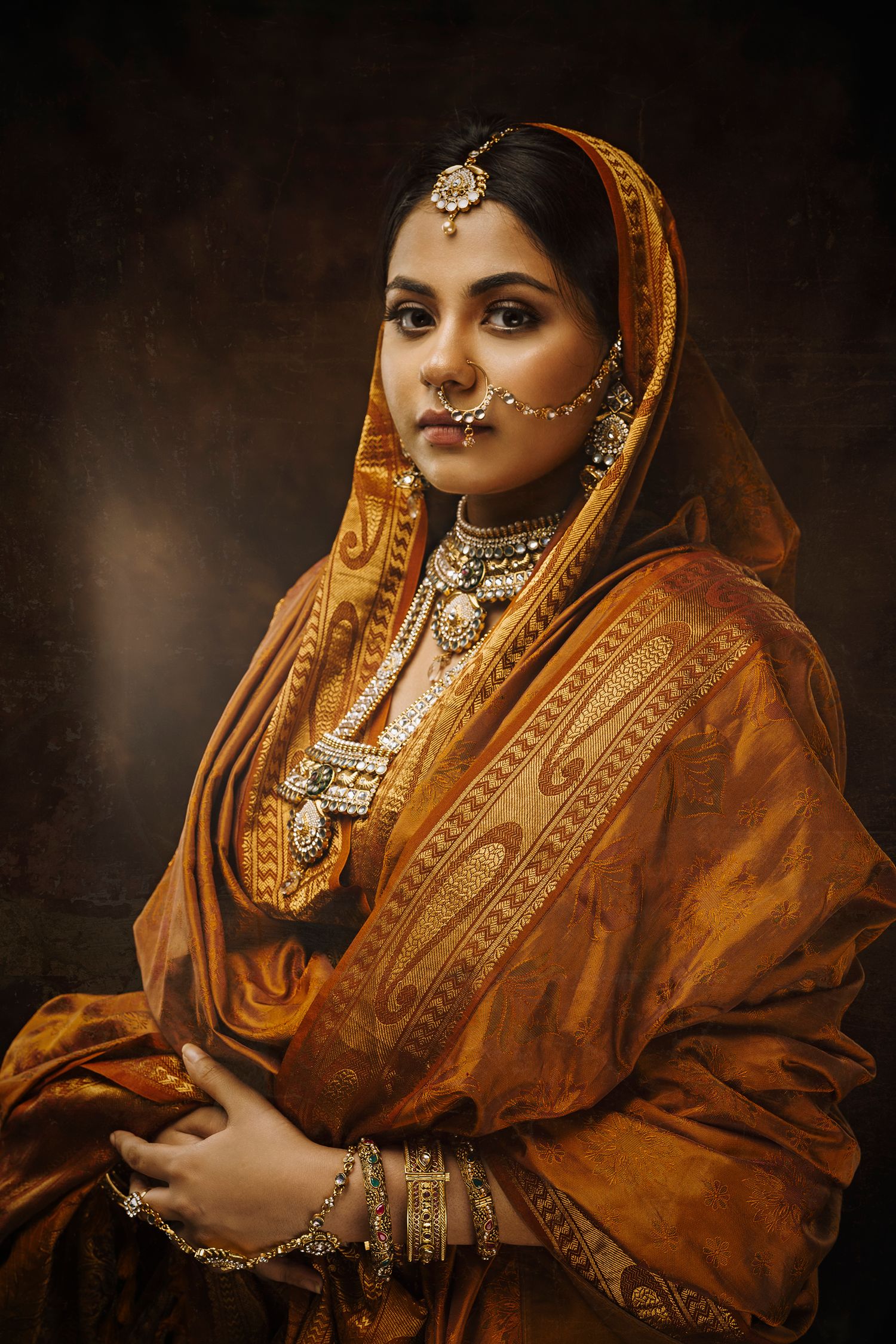 Traditional Indian bride in ornate orange and gold attire with elaborate jewelry.