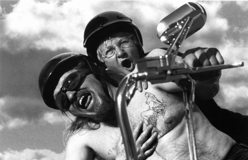 A black and white candid shot of two bandmates performing together with expressive emotions during a musical performance.