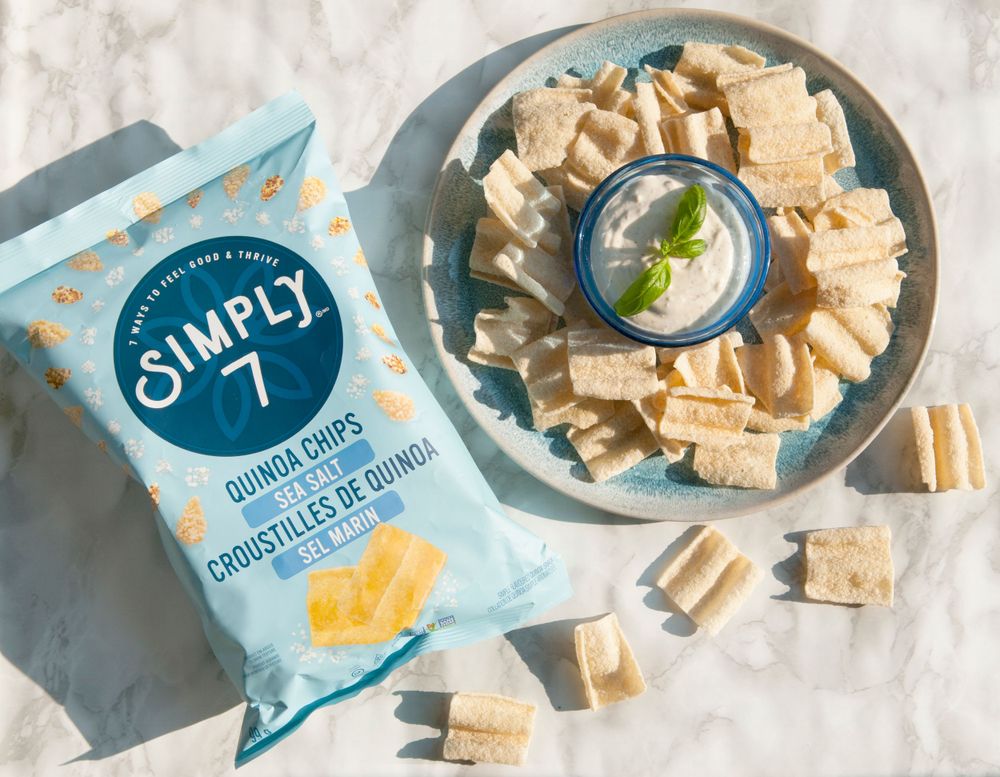Simply 7 snack chips with dip served on marble surface with packaging.