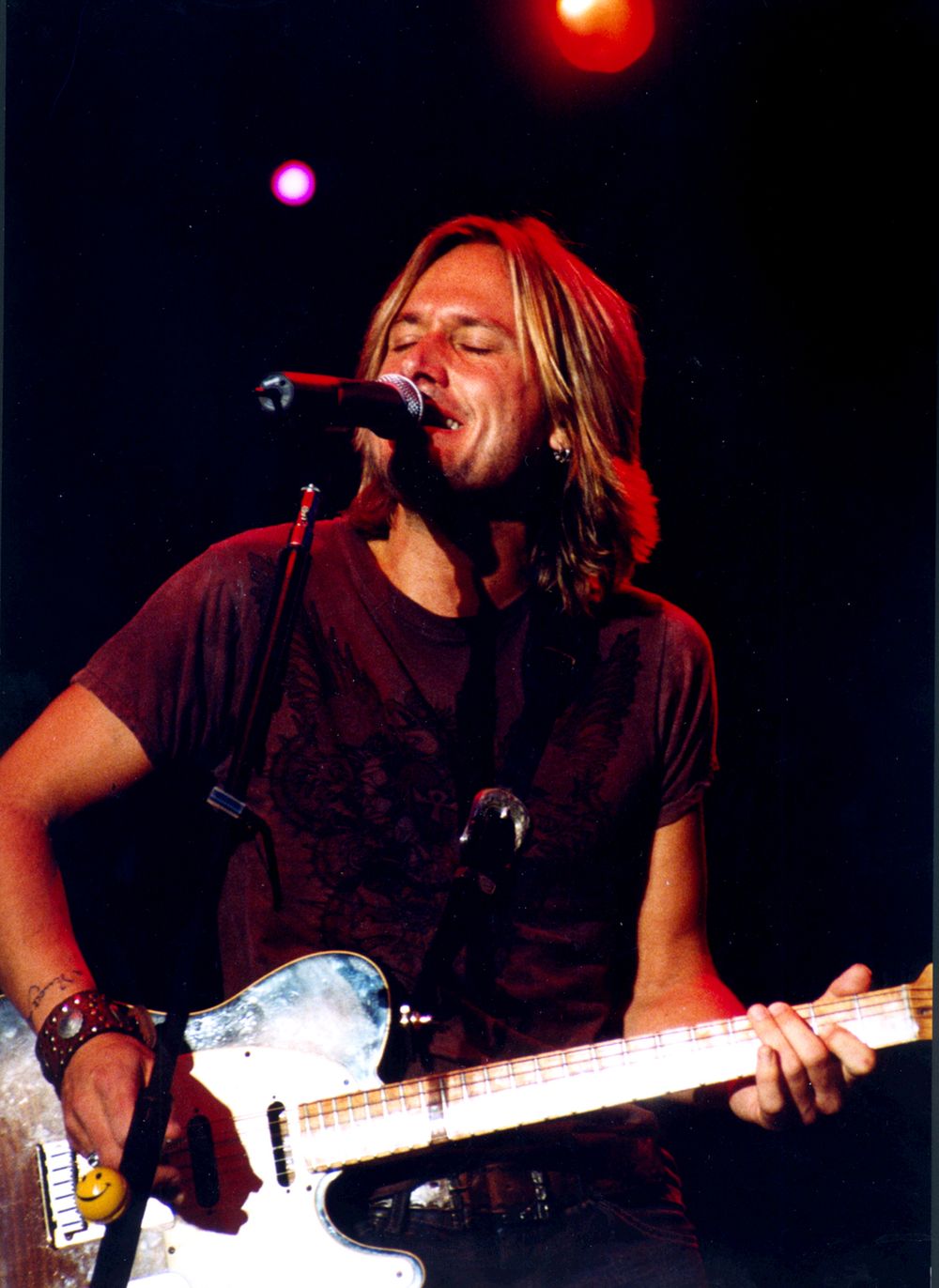 Rock musician performing on stage with guitar under dramatic lighting.
