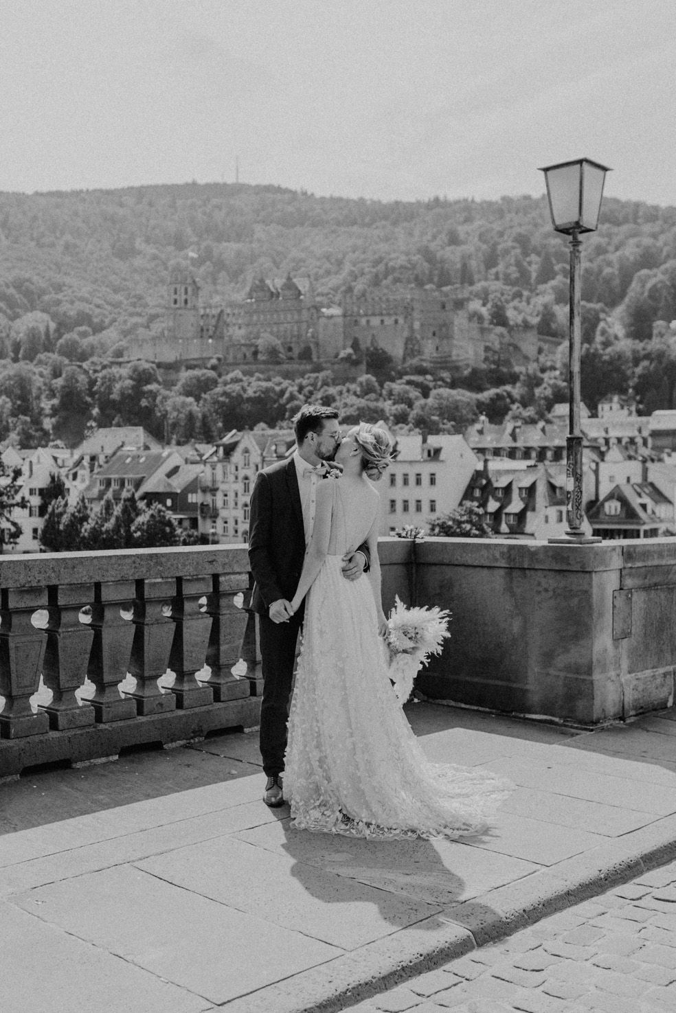 Schwarzweiß-Bild eines küssenden Brautpaars auf der alten Brücke in Heidelberg.