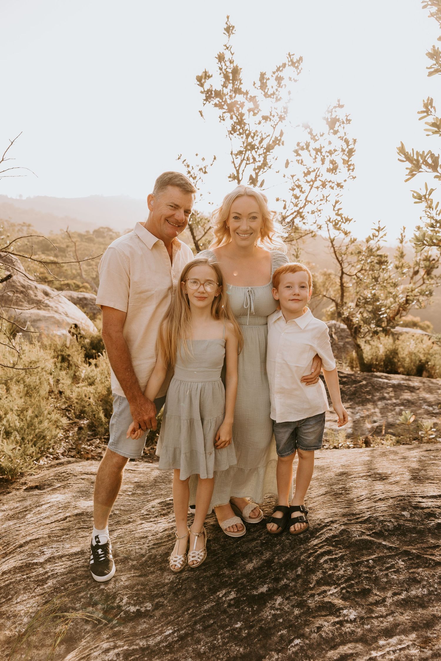 Family portrait session at sunset on rocky terrain with warm golden lighting.