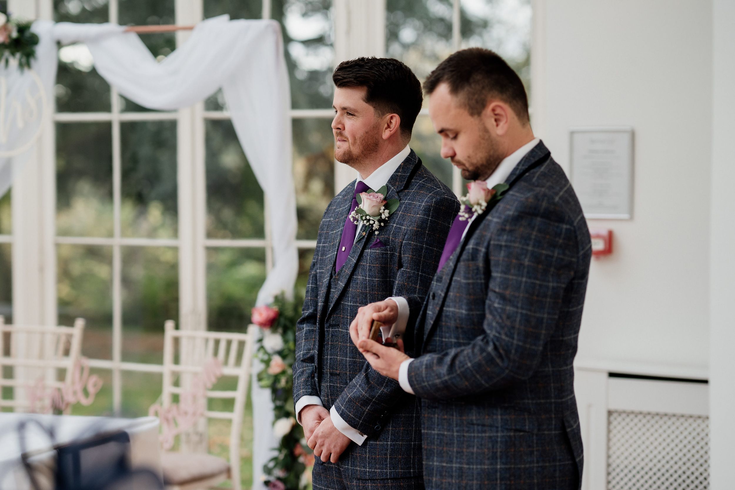 Two people in matching plaid suits sharing a moment during ceremony.